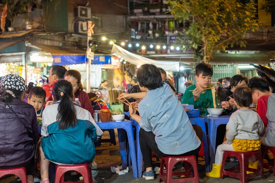 Family sitting at a street pho restaurant in Hanoi, Vietnam. Photo by Barbara Cameron Pix, Food & Travel Photographer